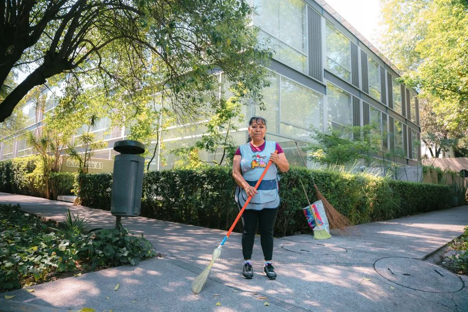 expertise-01 Jeune femme concentrée aux cheveux bouclés, à genoux sur le sol, en train de ranger des vêtements dans des cartons avant d’emménager dans son nouvel appartement